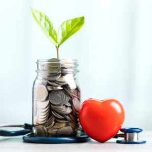 Financial wellness image showing a plant growing out of a glass jar of pennies, a small red heart, and a stethoscope.