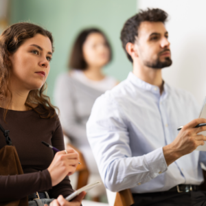 Employees in a classroom setting listening attentively and taking notes.
