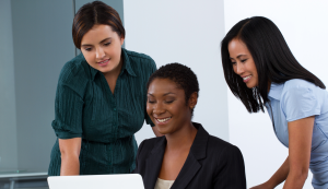 Three professional women looking at a laptop screen